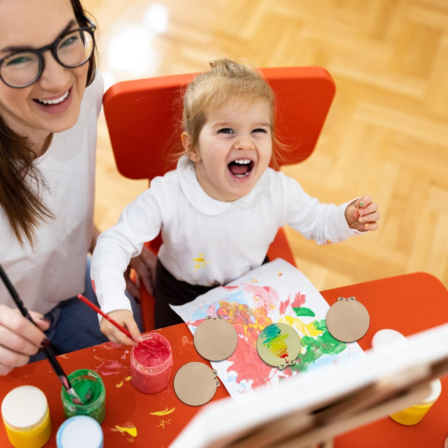 Woman and child engaged in a painting activity at a table.
