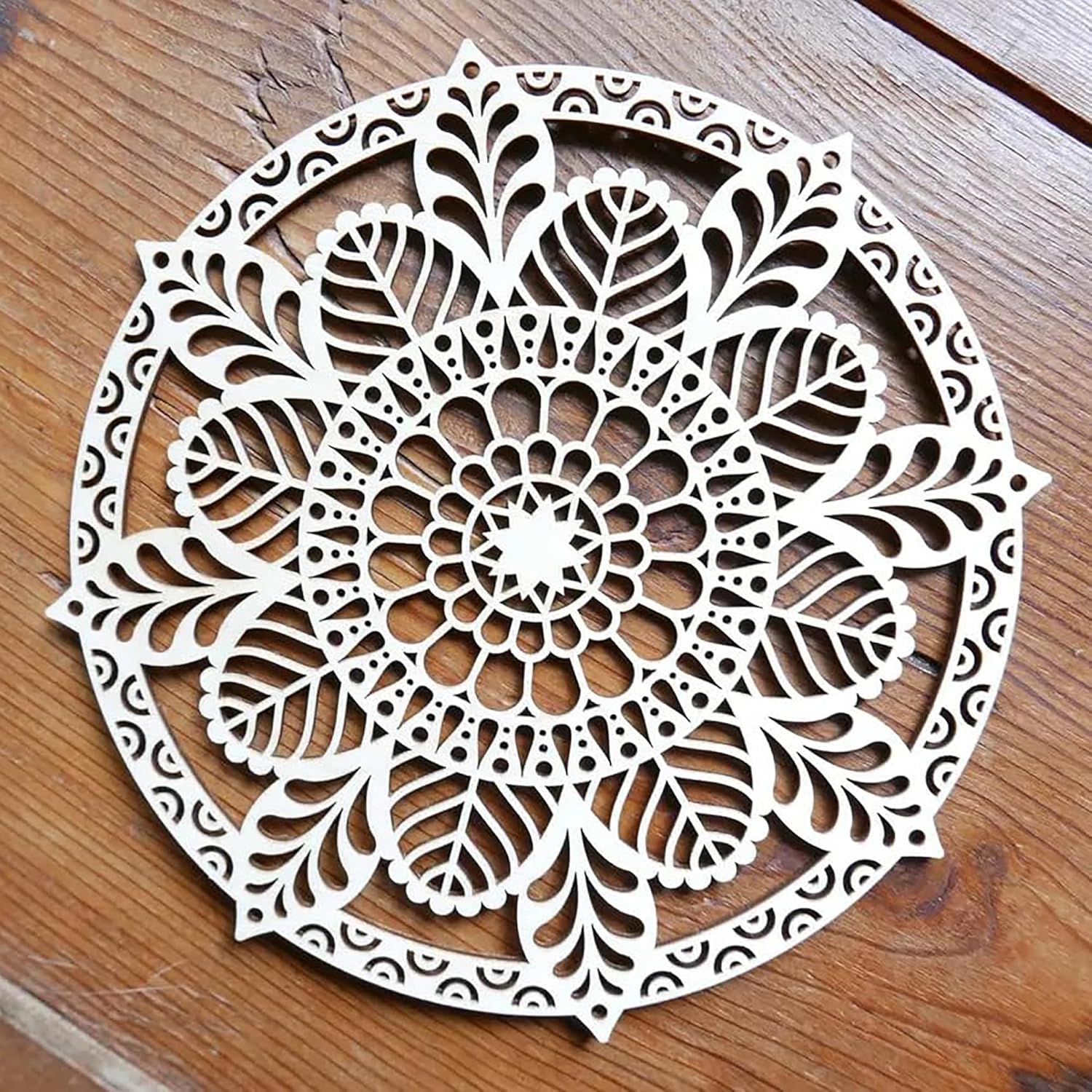 Decorative round wooden wall art with intricate leaf pattern on a wooden surface