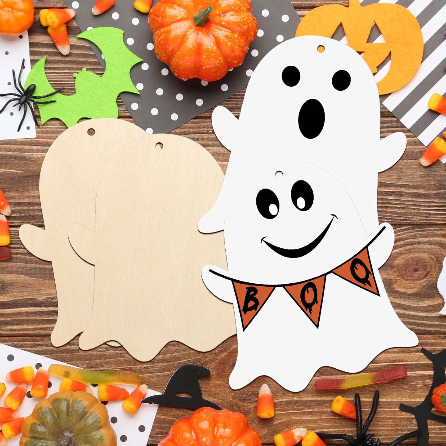 Halloween-themed craft project with a white ghost cutout and 'BOO' banner on a wooden surface.