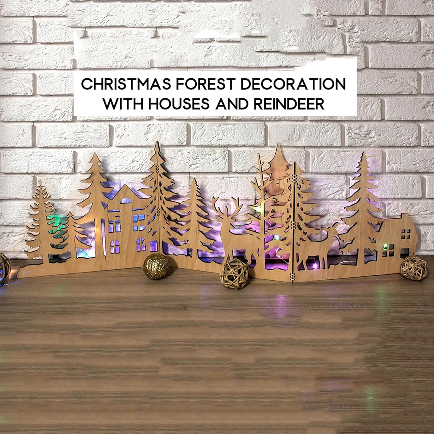 Wooden Christmas forest decoration with houses and reindeer on a wooden surface and brick wall background.