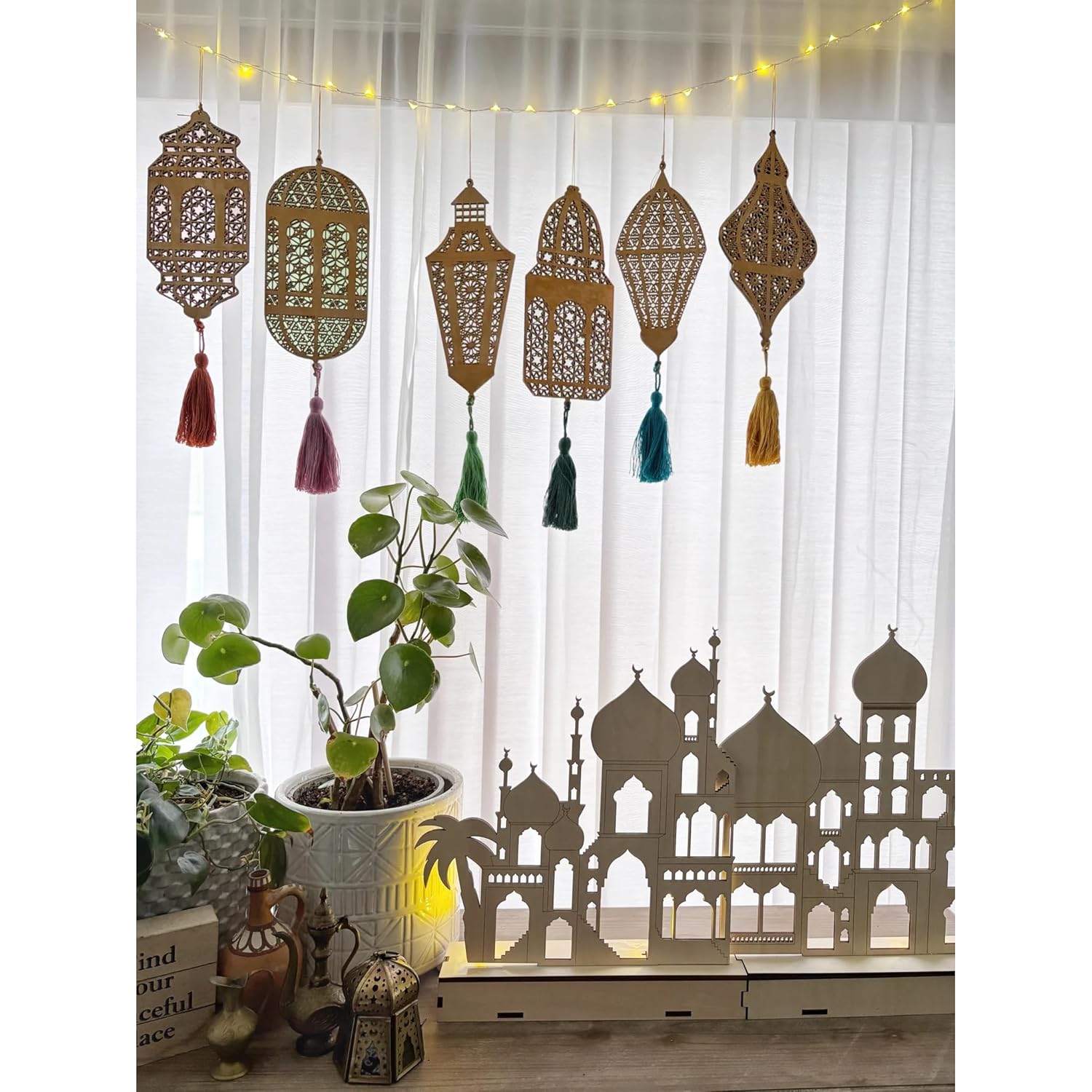 Decorative curtain with lanterns and tassels hanging above a silhouette of a building.