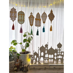 Decorative curtain with lanterns and tassels hanging above a silhouette of a building.