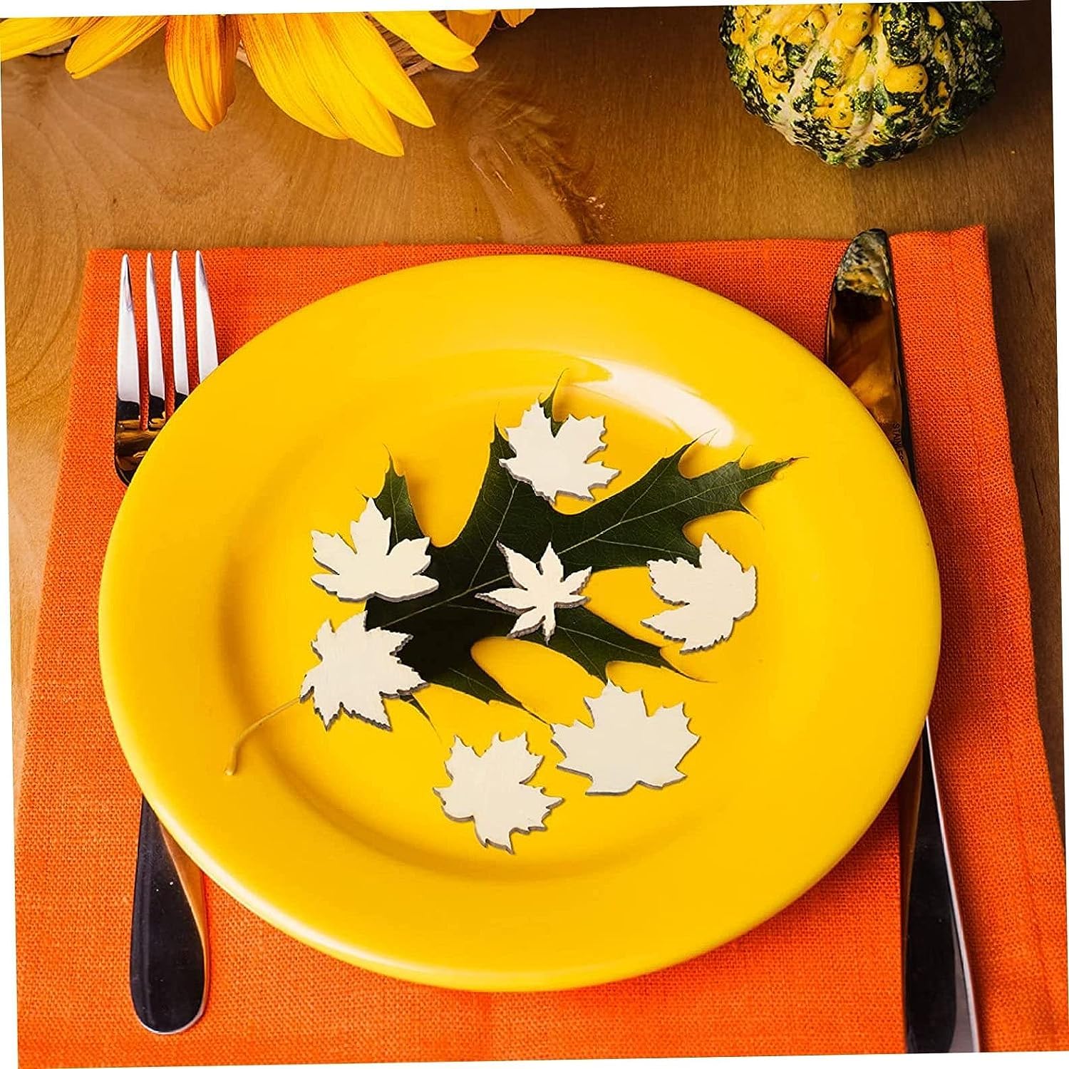 Yellow plate with leaf decorations on a red napkin with cutlery