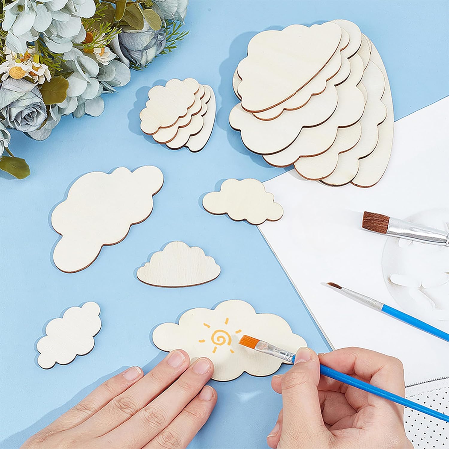 Crafting activity with cloud-shaped wooden pieces on a blue surface.