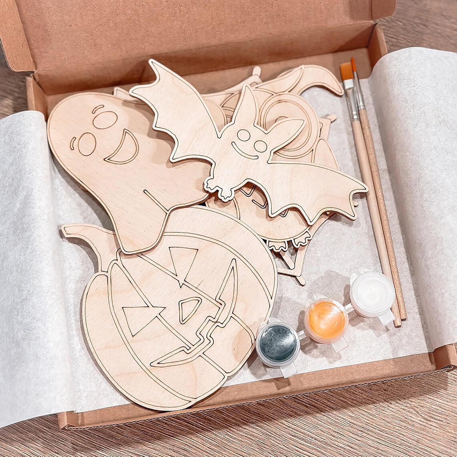 Wooden Halloween-themed cutouts with paint supplies in a box