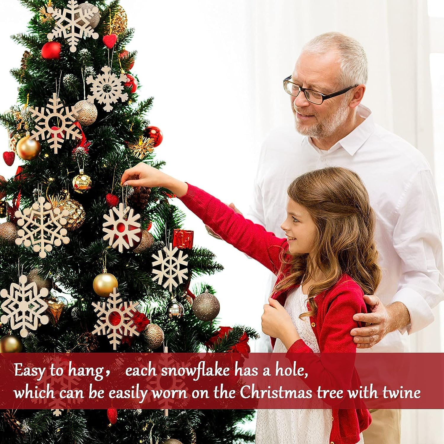 Man and young girl decorating a Christmas tree with snowflake ornaments.