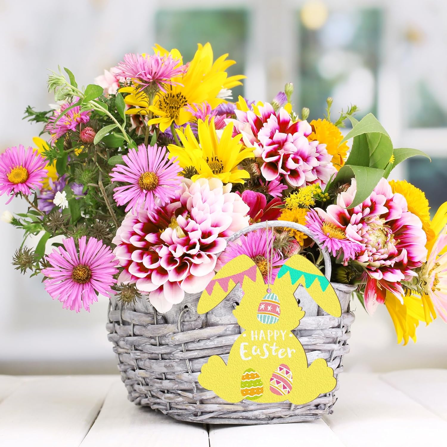 Basket of flowers with a 'Happy Easter' bunny tag on a blurred background
