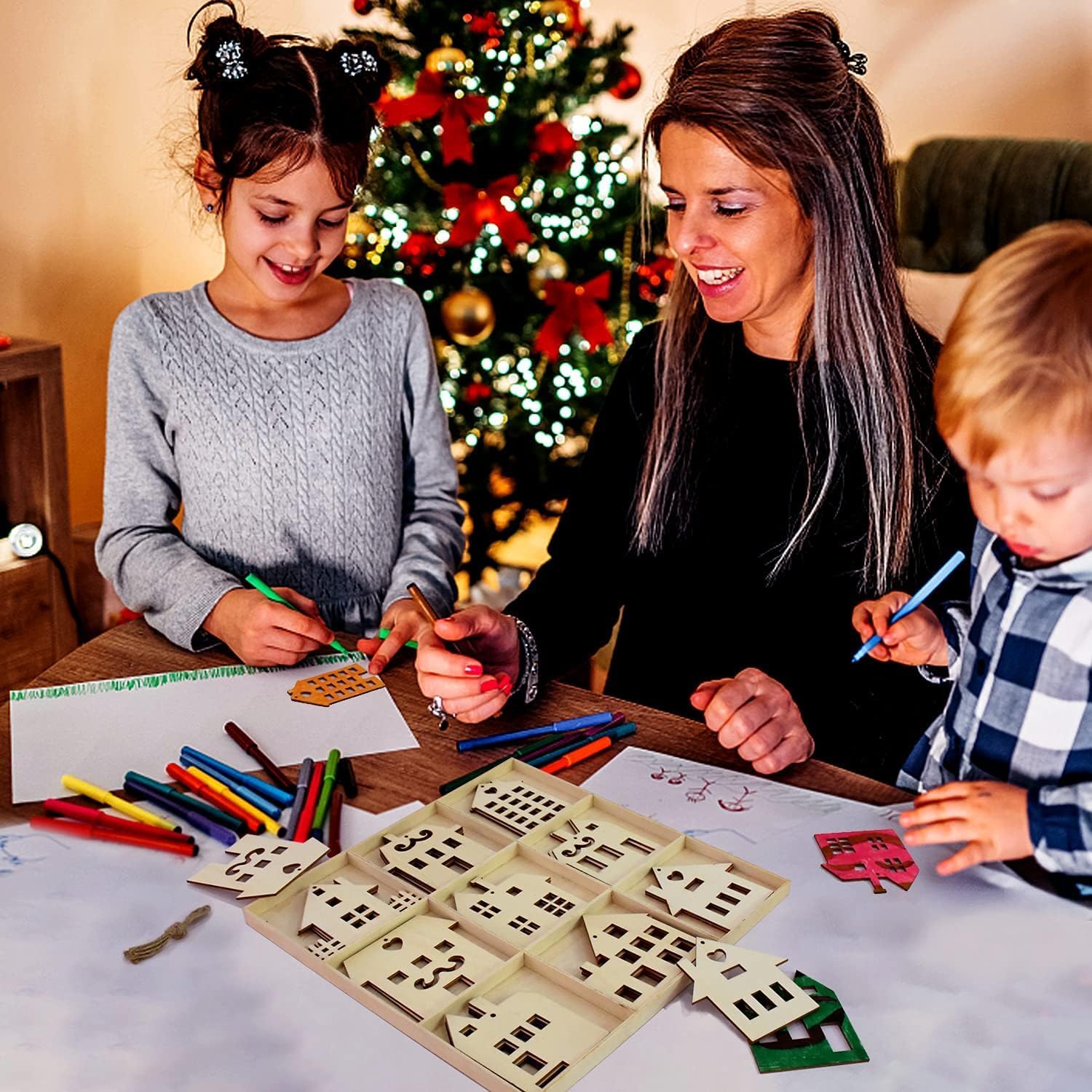 Woman and two children engaging in a craft activity with Christmas decorations in the background