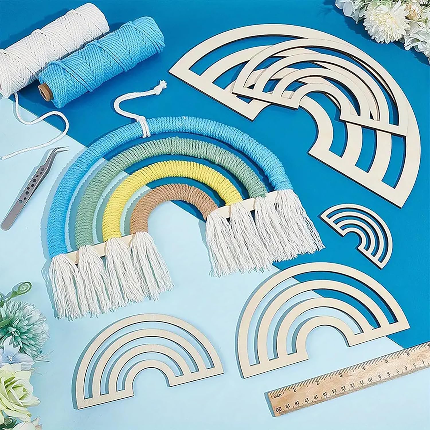 Macrame rainbow wall hanging with wooden rainbow shapes and crafting materials on a blue background.