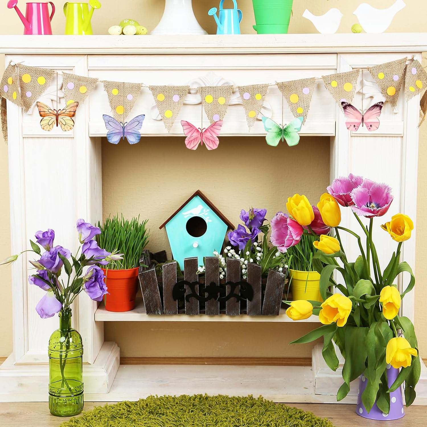 Decorative shelf with flowers, a birdhouse, and a small fence on a shelf with a colorful banner above.