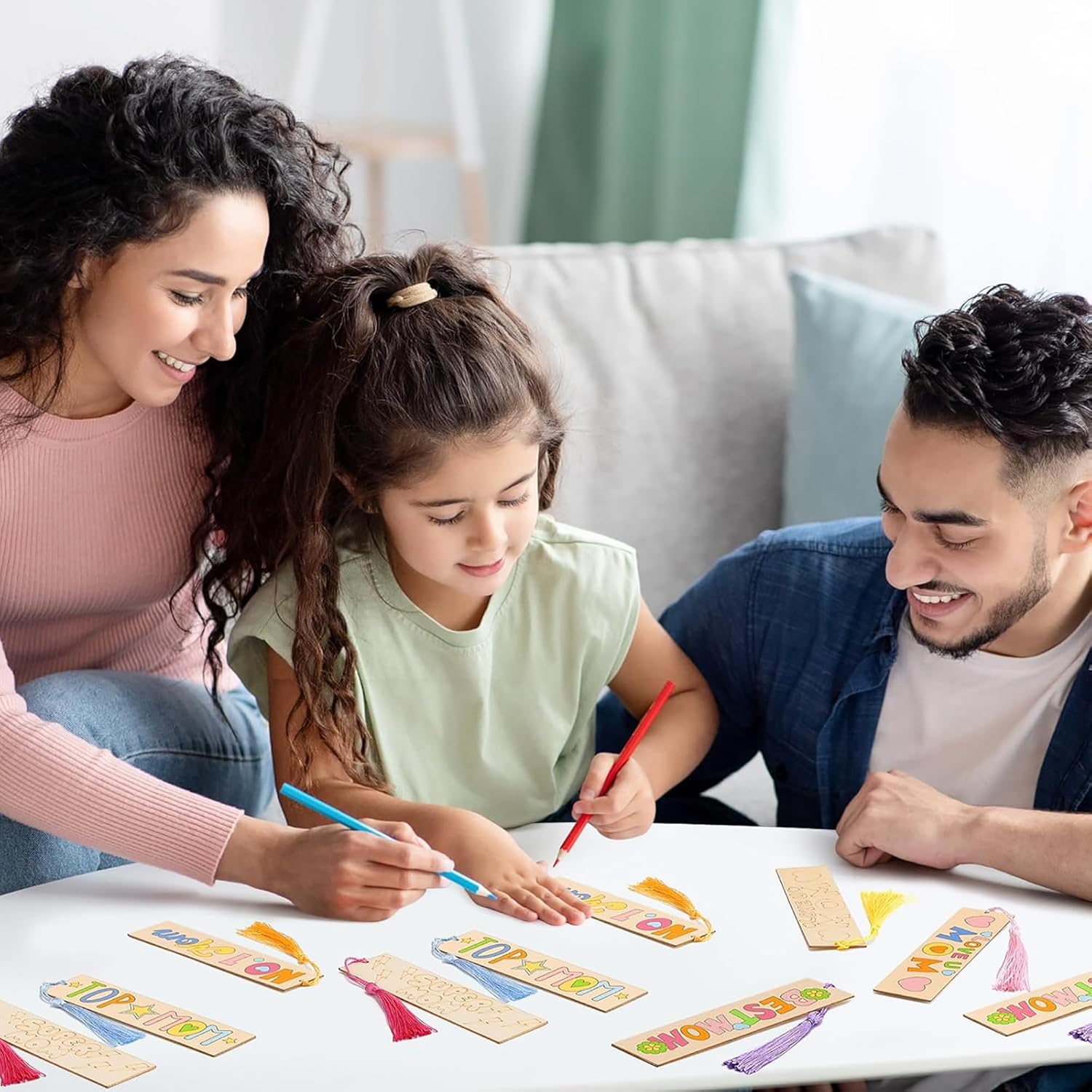 Family of three sitting around a table with colorful cards, smiling and engaged in an activity.