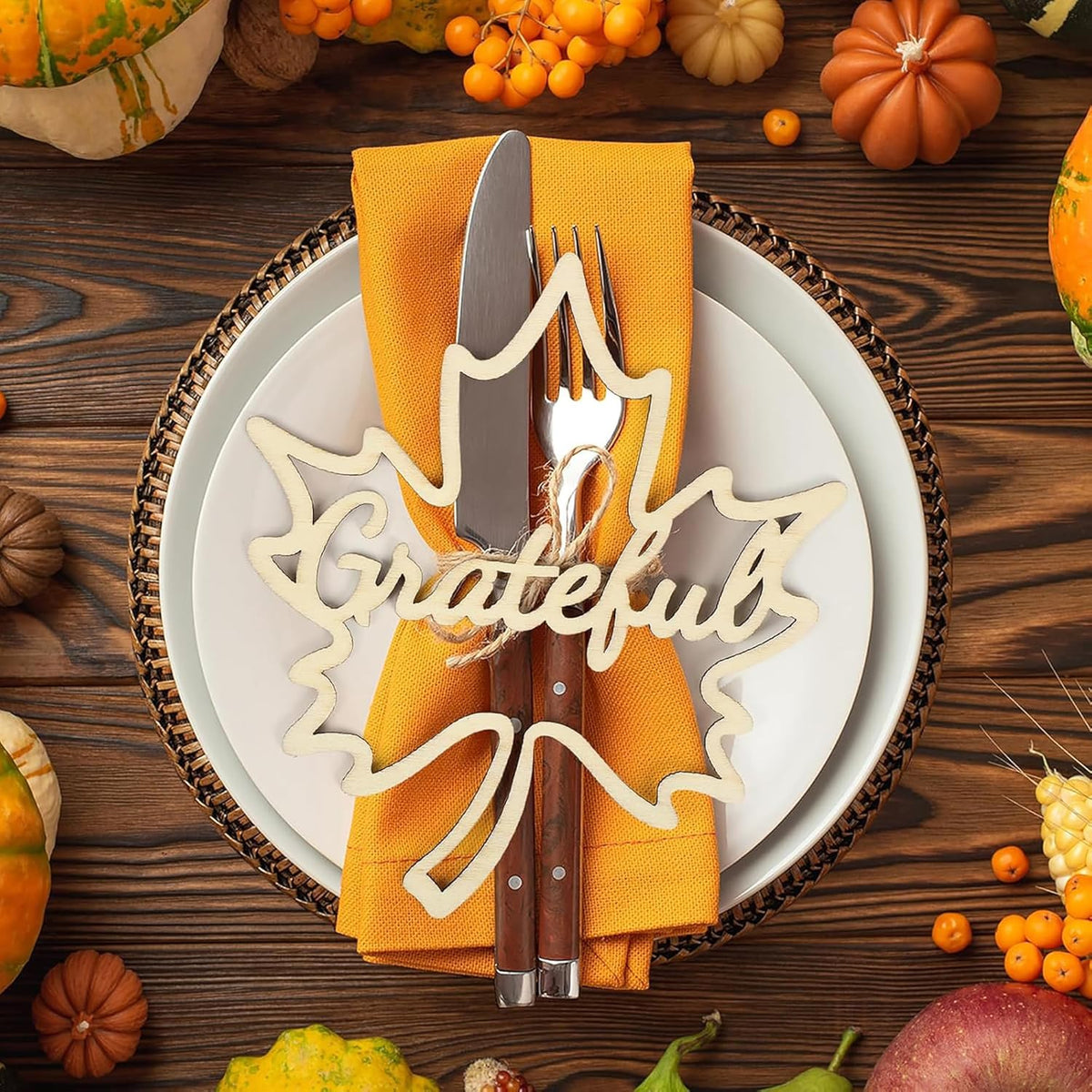 Thanksgiving table setting with 'Grateful' decoration, knife, fork, and yellow napkin on a wooden background.