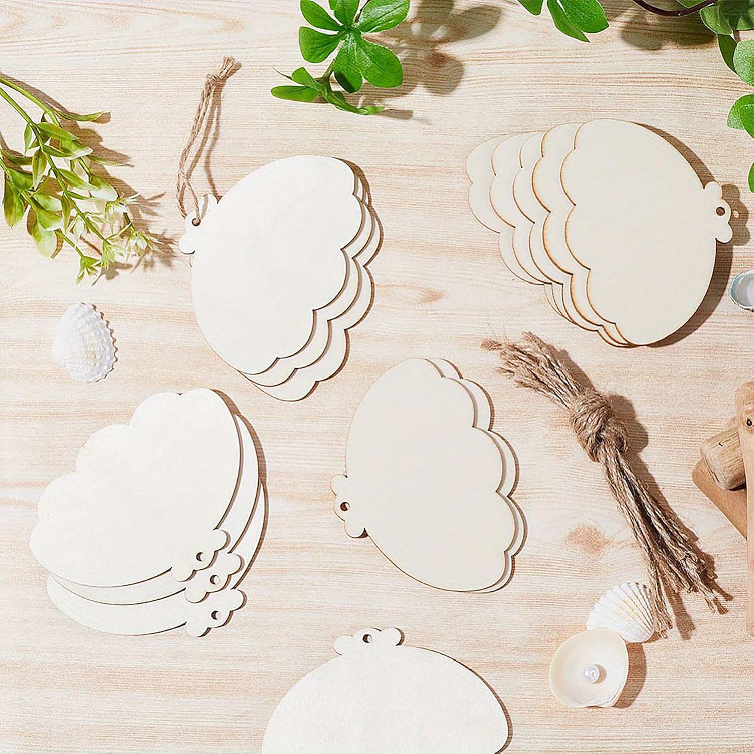 Wooden cloud-shaped tags on a wooden surface with greenery and shells.