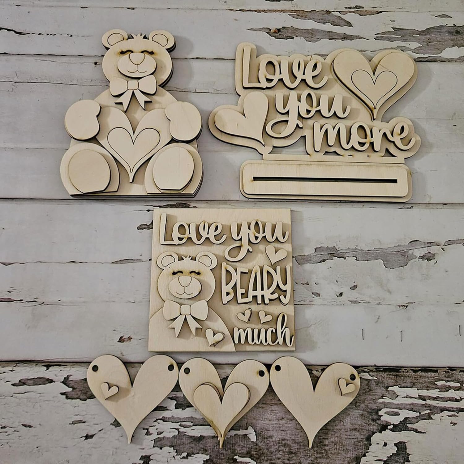 Wooden decorative items with teddy bear and heart designs on a rustic wooden background