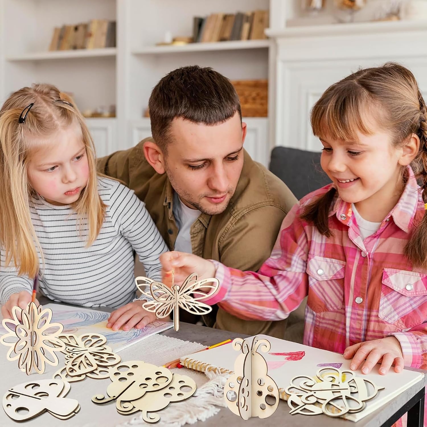 Man and two young girls working on a craft project with wooden butterfly shapes.