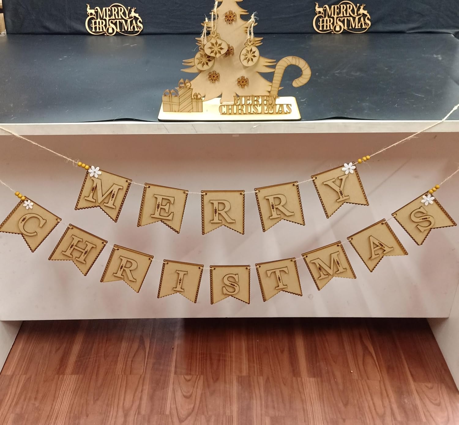 Decorative 'Merry Christmas' banner with a gold Christmas tree on a blue surface.