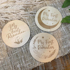 Three wooden coasters with 'My First Ramadan' engraving on a textured fabric background.