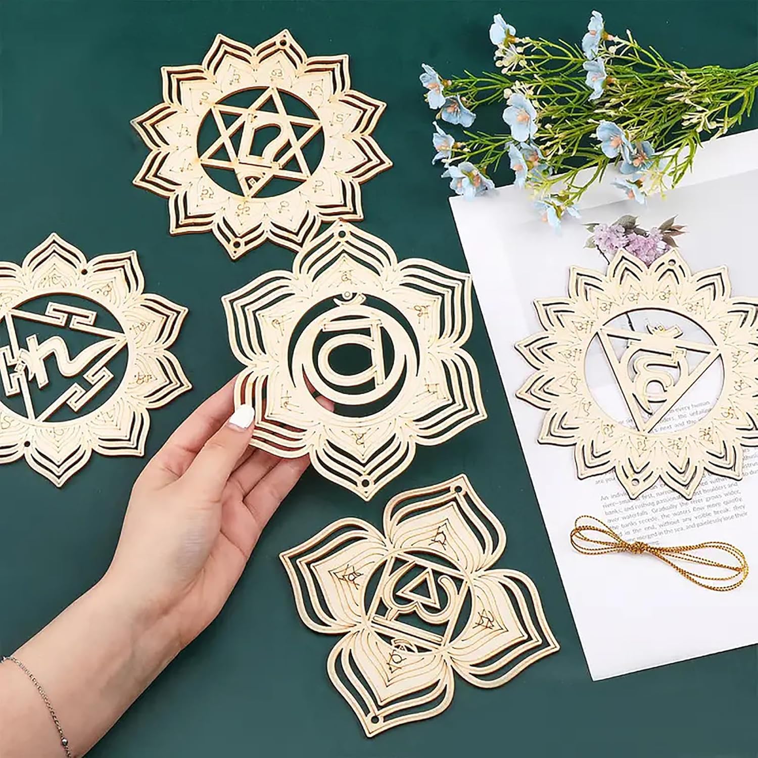 Decorative paper cutouts with intricate designs on a green surface with flowers and a letter.