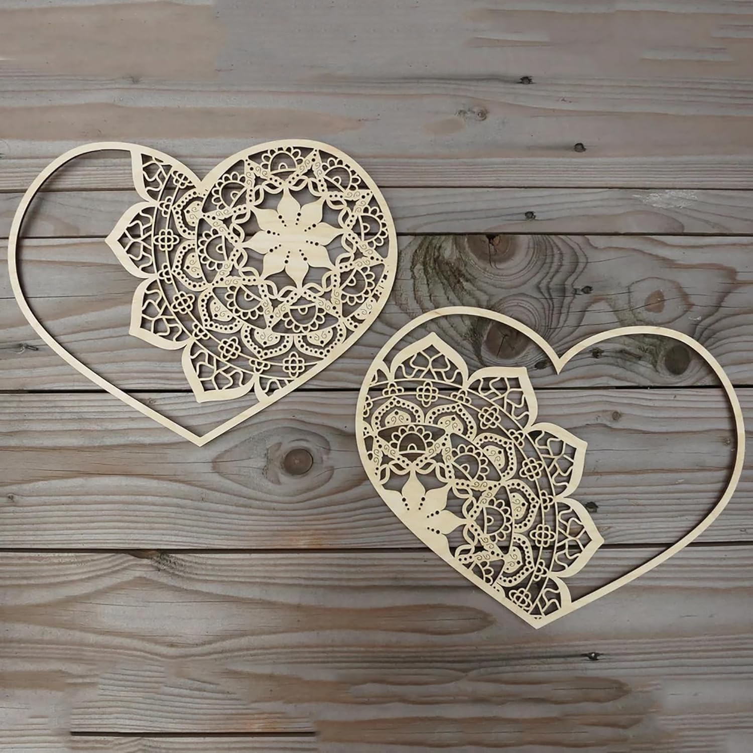 Two heart-shaped laser cut decorative pieces on a wooden surface