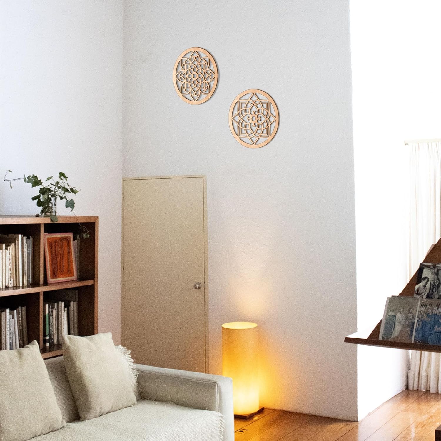 Decorative wall art on a white wall with a lamp and bookshelf in a room.