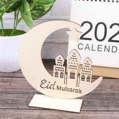 Wooden crescent moon with 'Eid Mubarak' and mosque silhouette on a wooden surface with a calendar in the background.