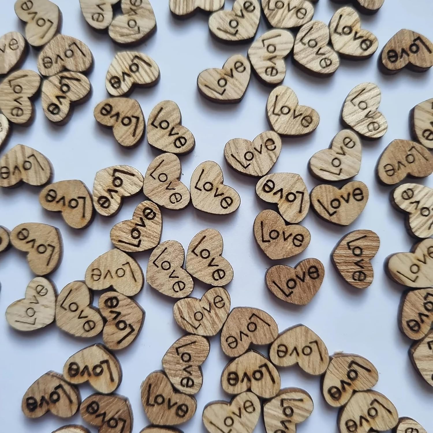 Wooden hearts with 'love' engraved on them scattered on a light blue background