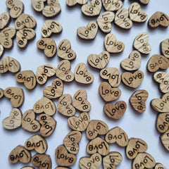 Wooden hearts with 'love' engraved on them scattered on a light blue background