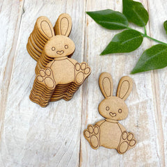 Stack of wooden bunny shapes on a light wooden surface with green leaves.