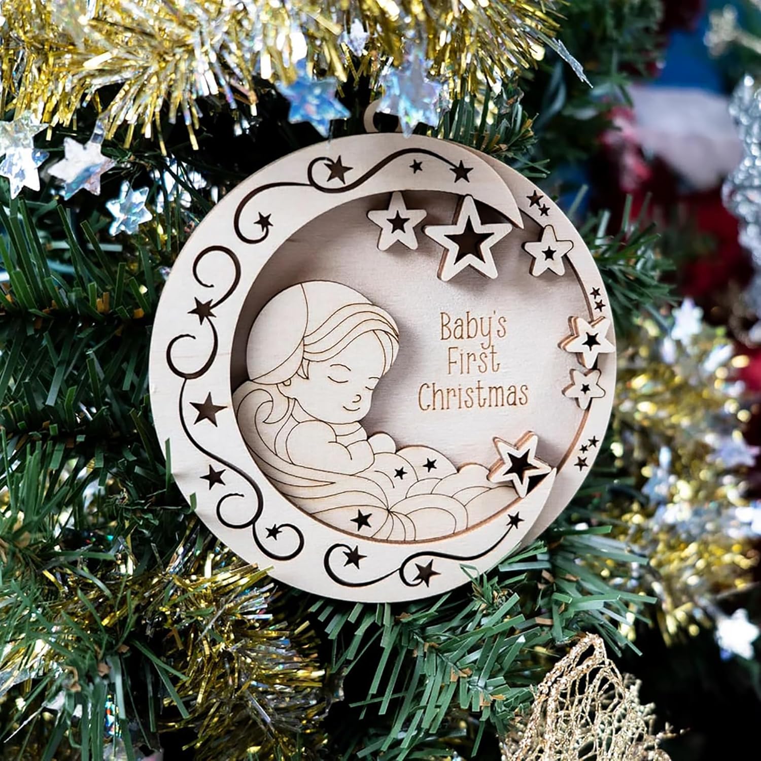 Wooden ornament with baby design and 'Baby's First Christmas' text on a decorated tree.