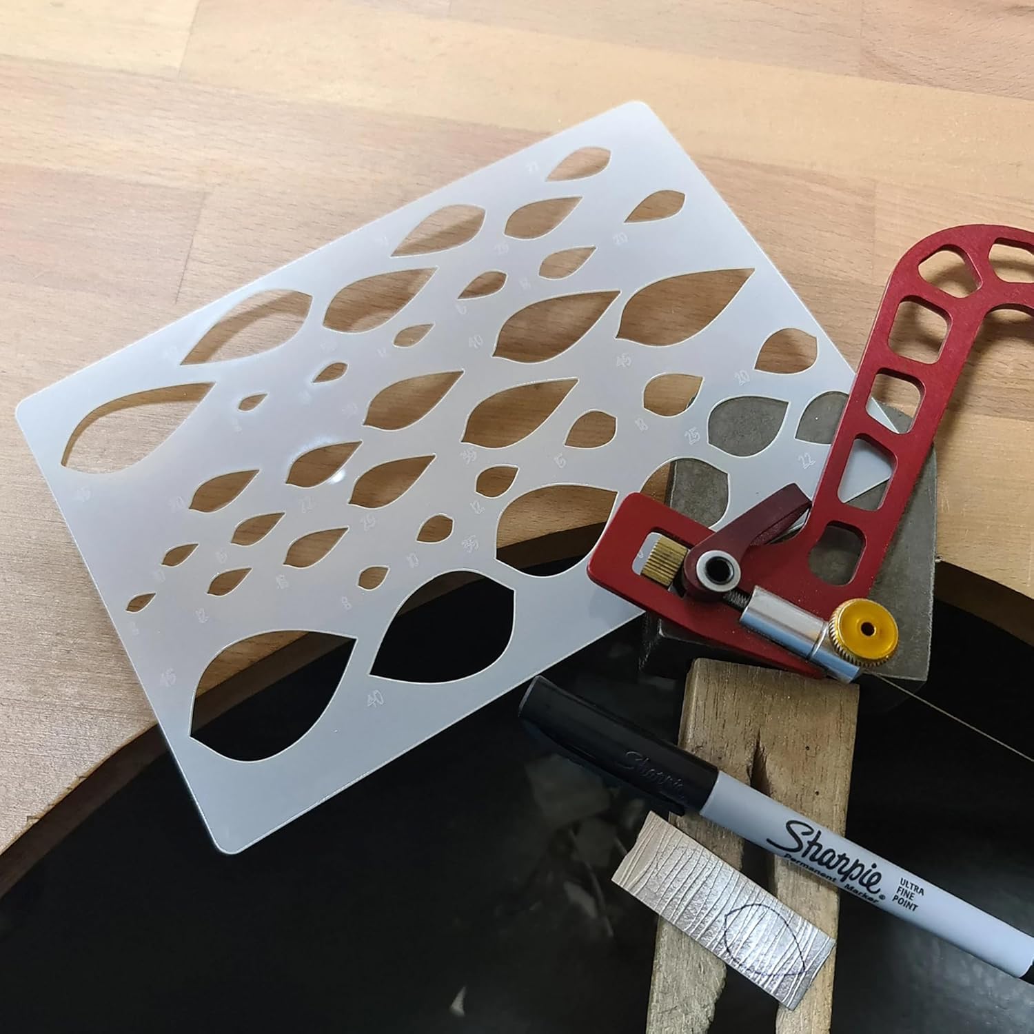 Stencil with leaf patterns on a wooden surface with a Sharpie marker.