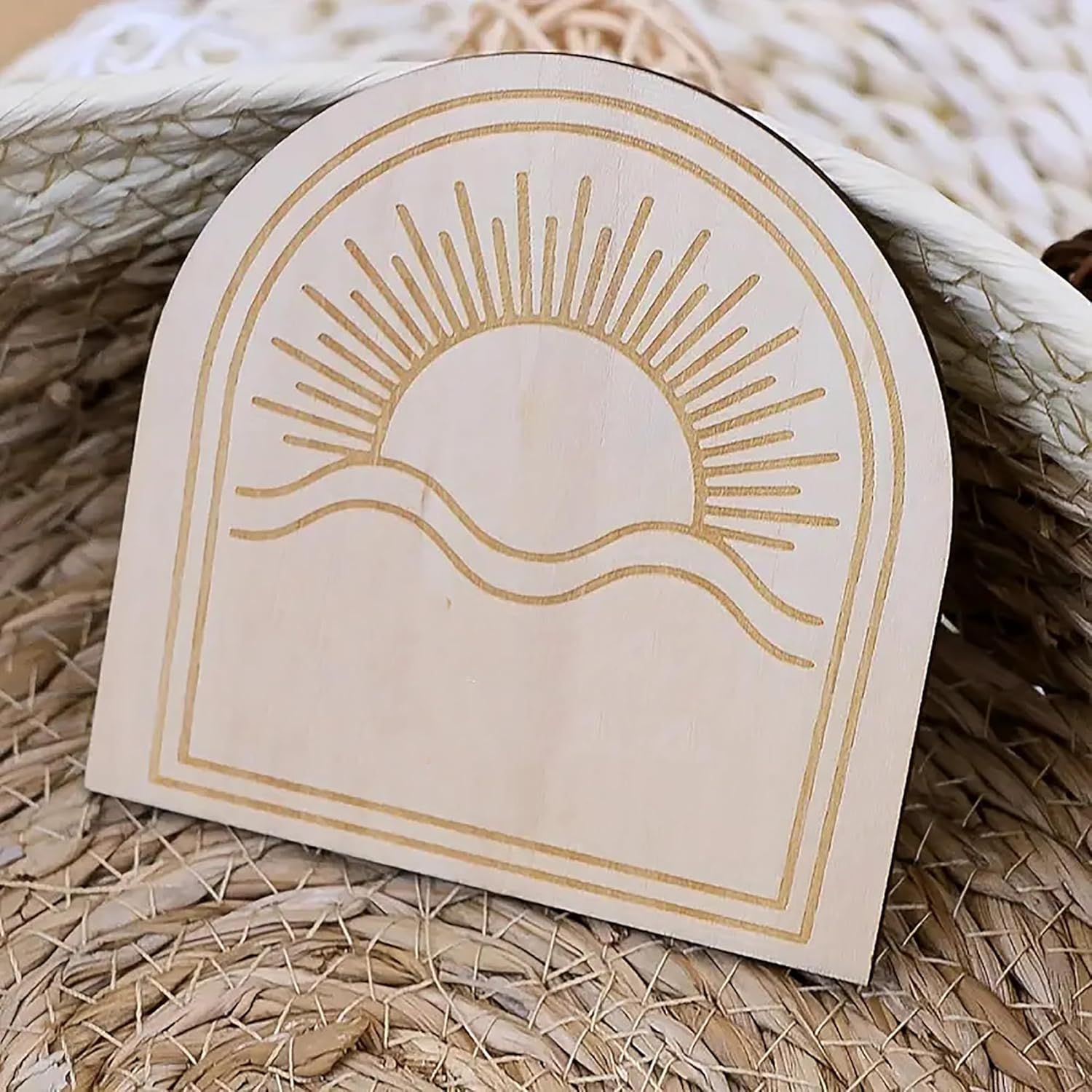 Decorative card with sun and mountain design on a woven surface