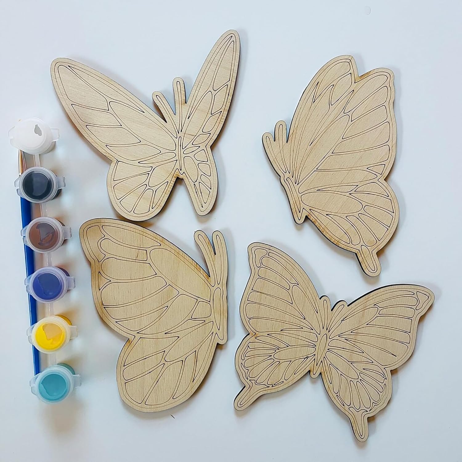 Four wooden butterfly shapes with paint containers on a white background