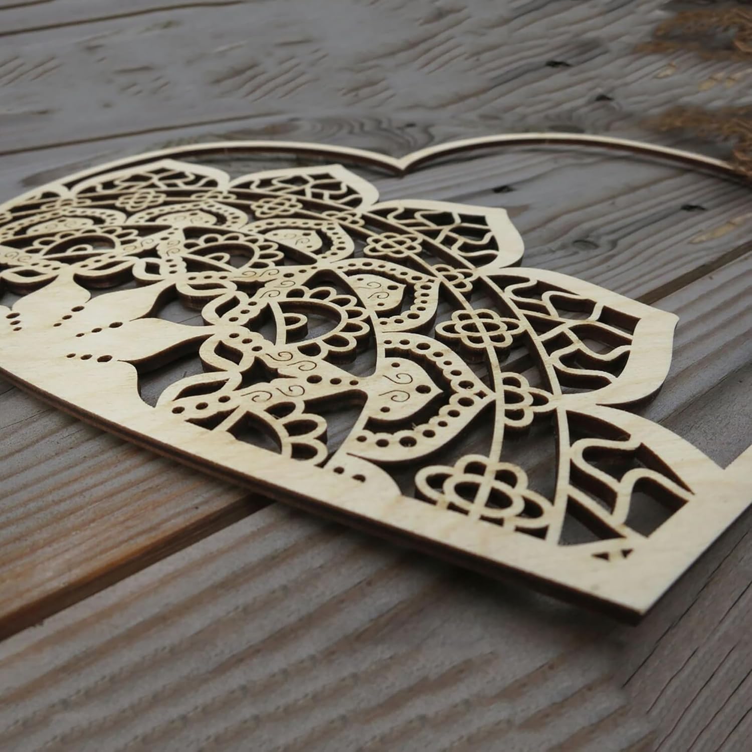 Wooden heart-shaped cutout with intricate patterns on a wooden surface