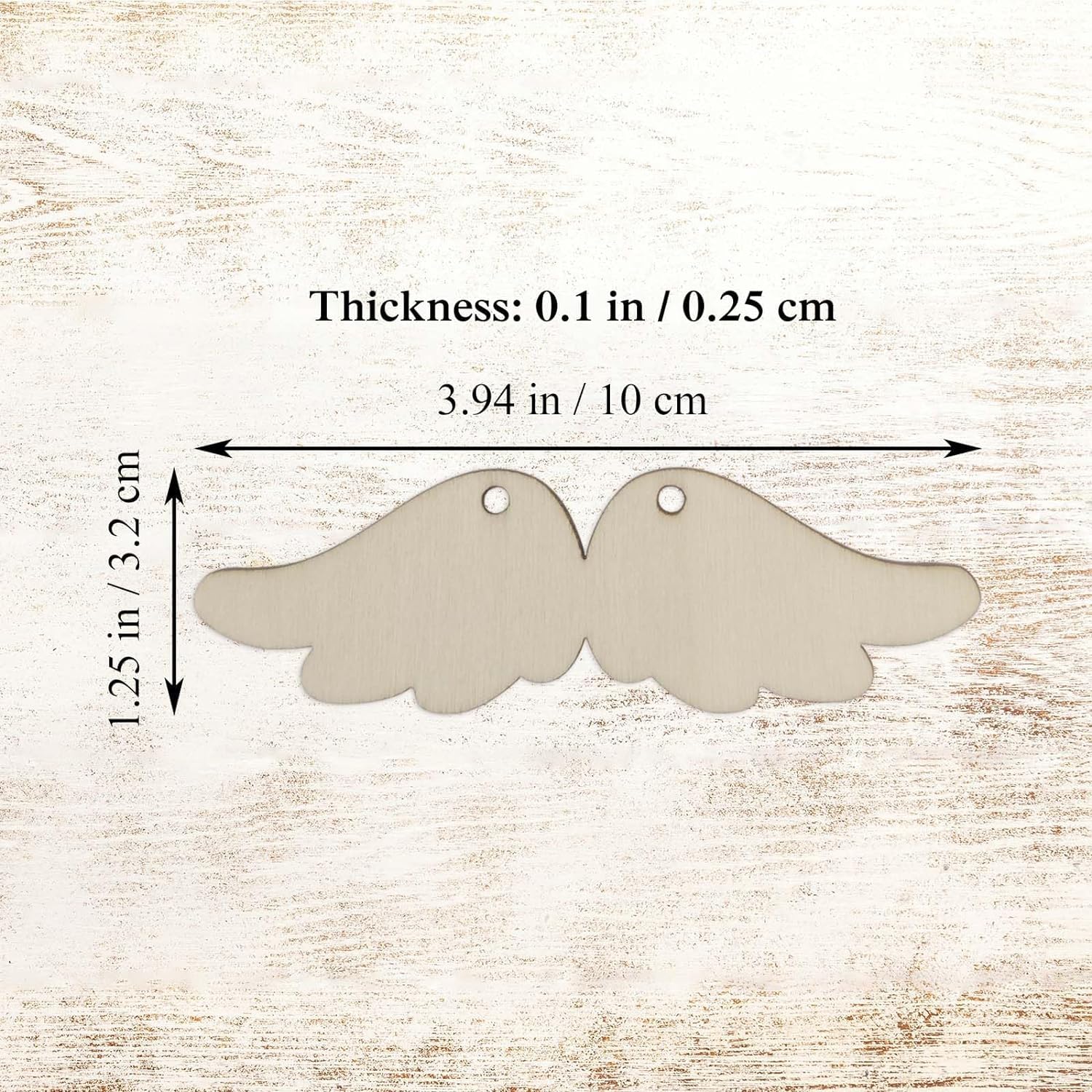 Two angel wing-shaped metal tags with measurements on a wooden background