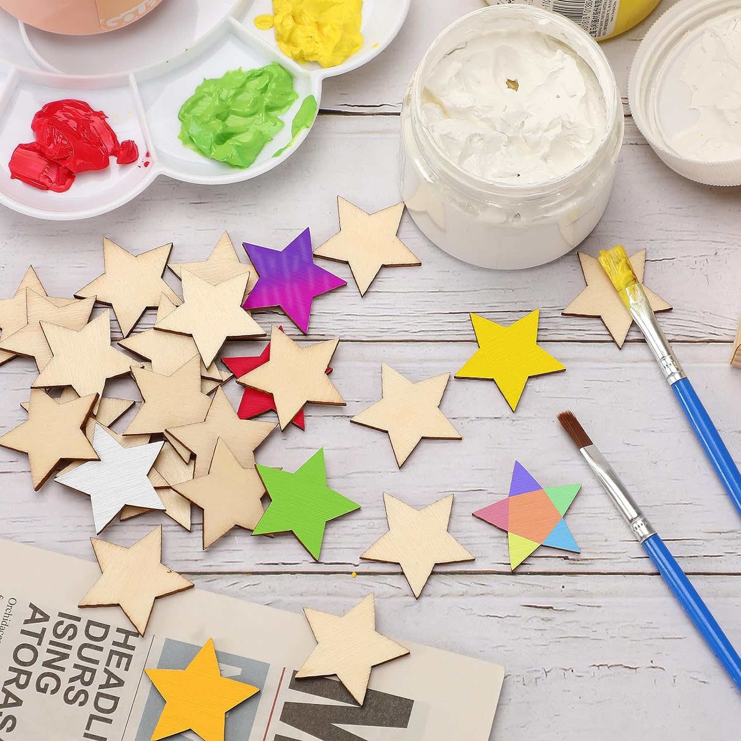 Colorful star-shaped craft materials on a table with paint and brushes.