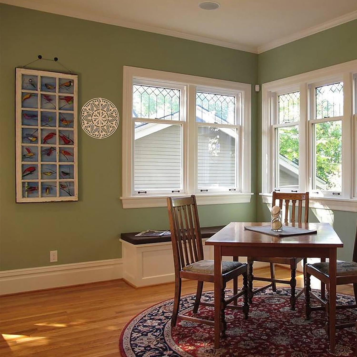 Dining room with wooden table and chairs, green walls, and large windows.