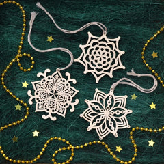 Decorative snowflake ornaments on a textured green background with gold beads and stars.