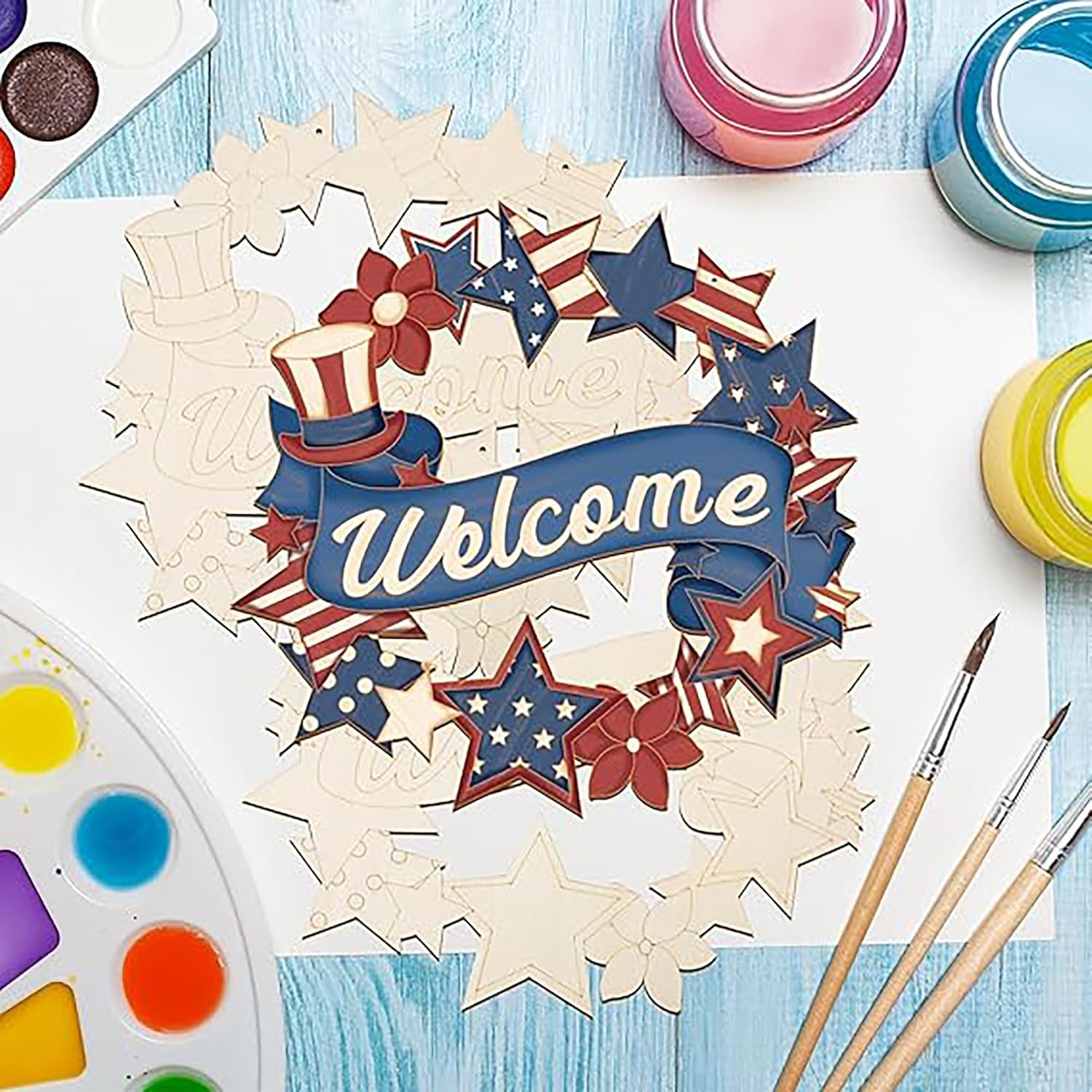 Wooden wreath with 'Welcome' text and patriotic design on a blue surface with paint supplies.