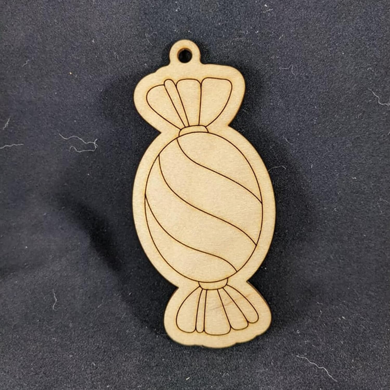 Wooden candy-shaped pendant on a dark background