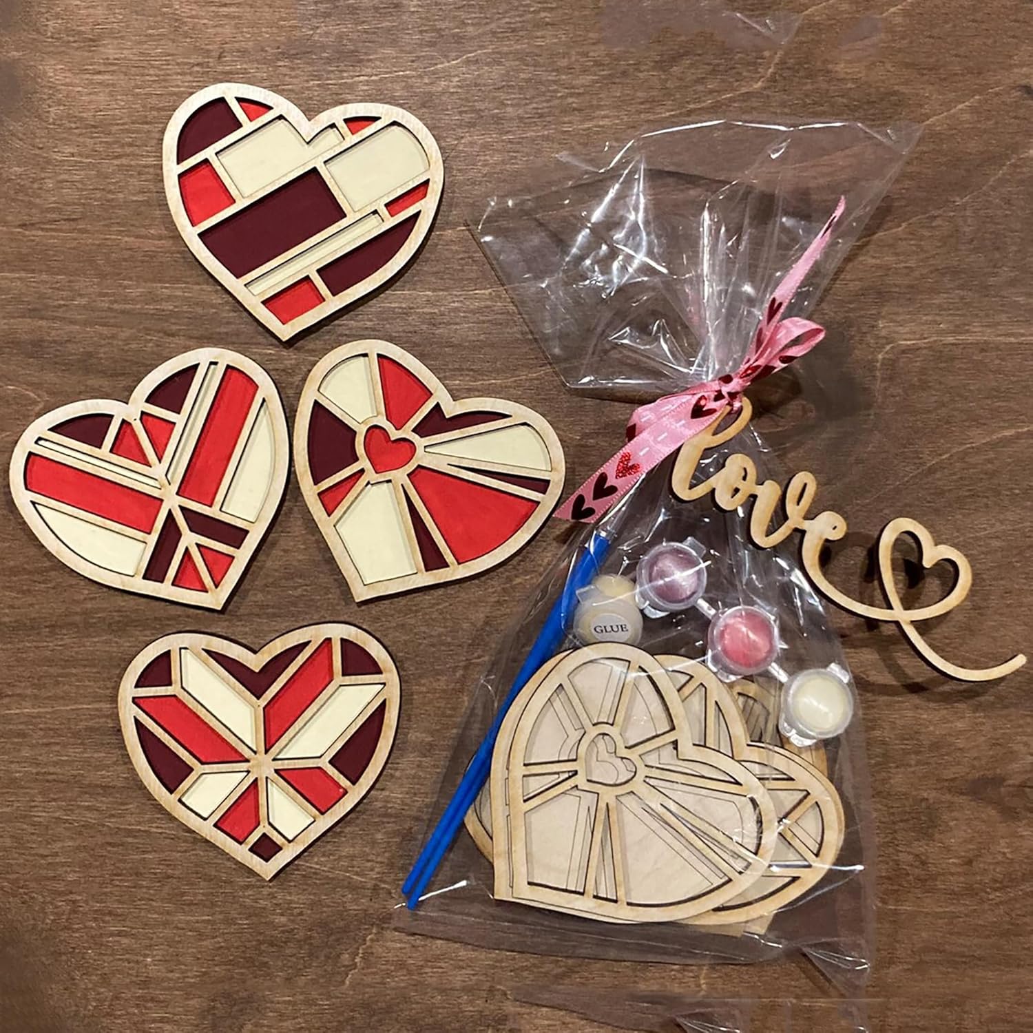 Heart-shaped wooden decorations on a wooden surface with a clear bag containing small items.