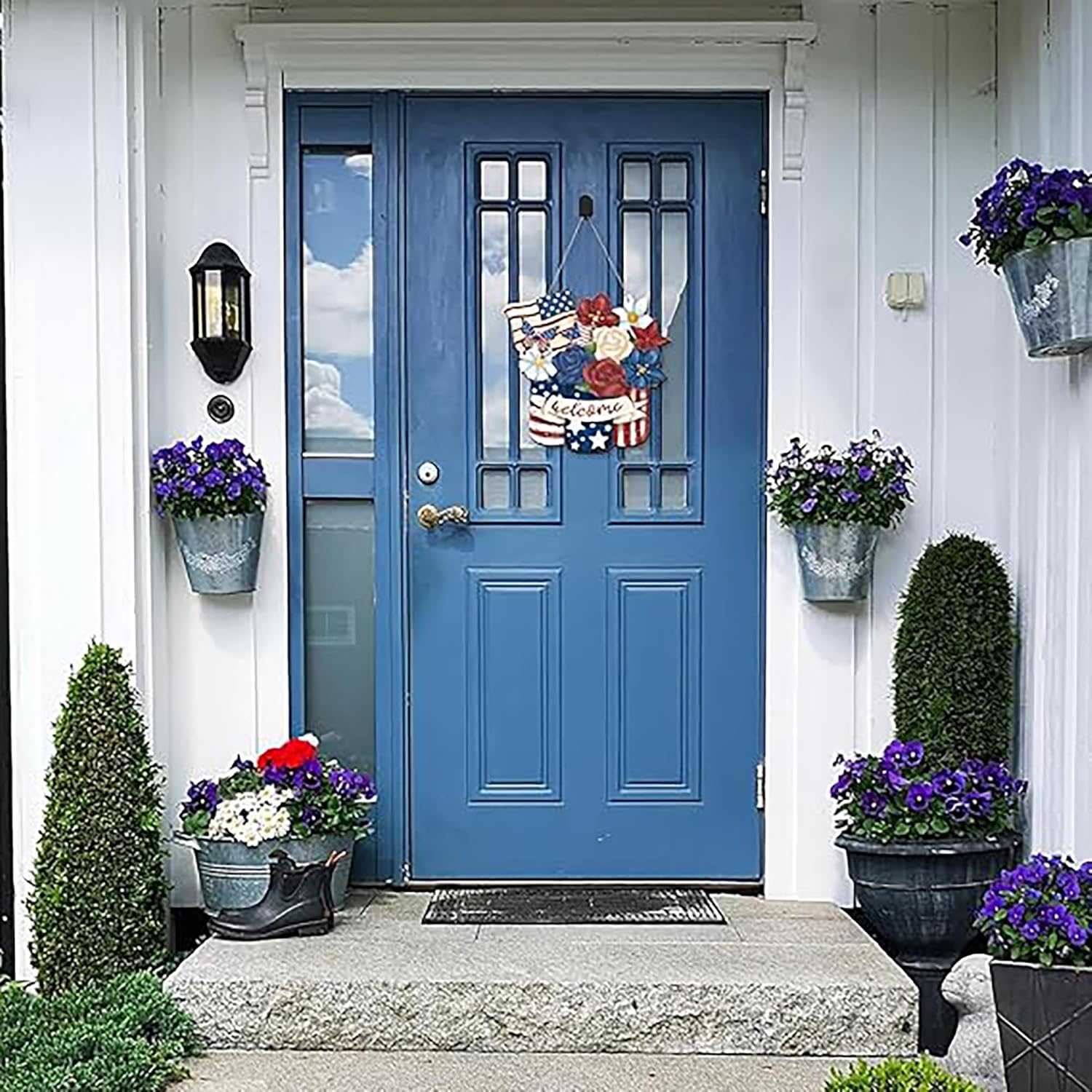 Blue front door with decorative elements and flowers on a white house exterior.