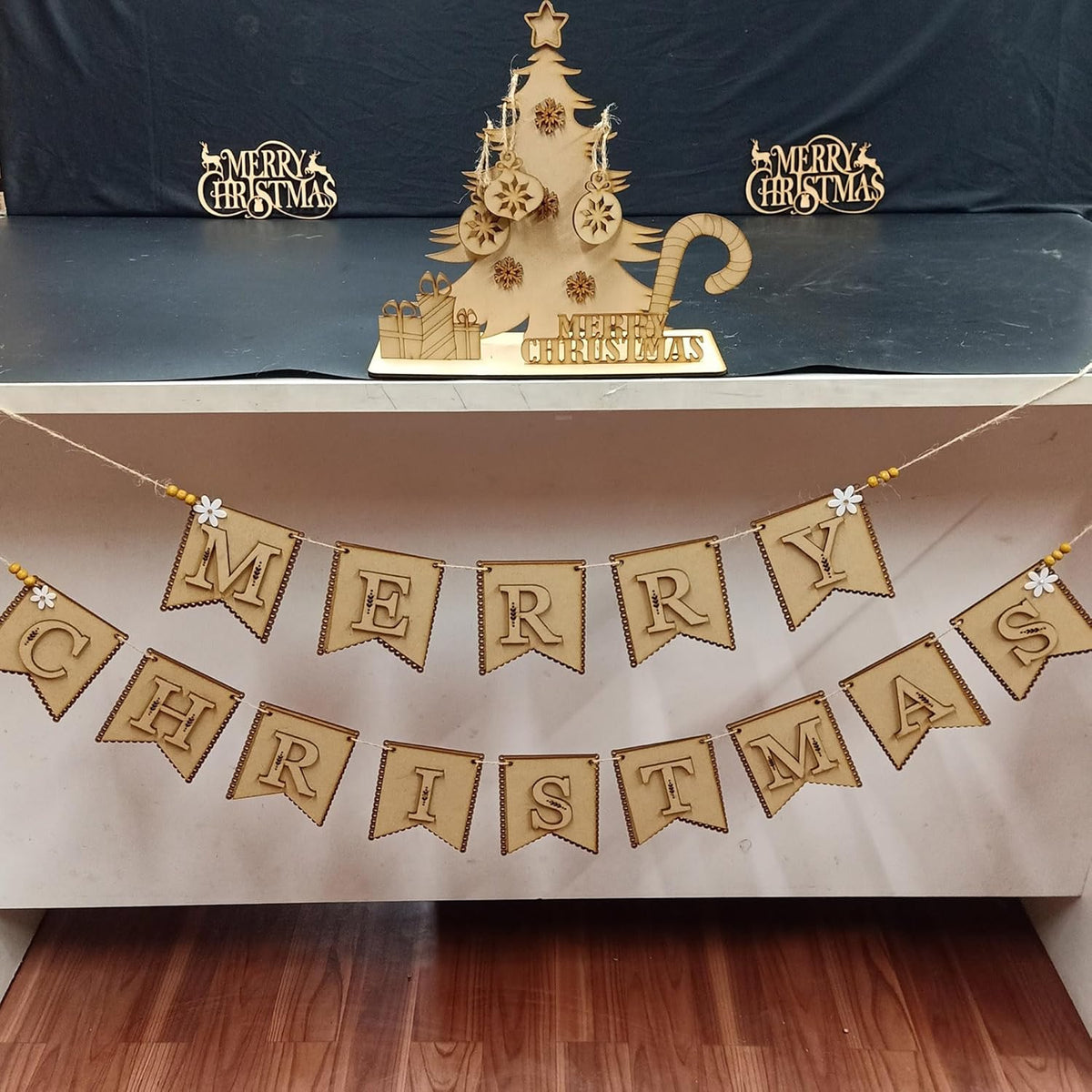 Decorative Christmas tree and 'Merry Christmas' banner on a white surface with a dark blue backdrop.