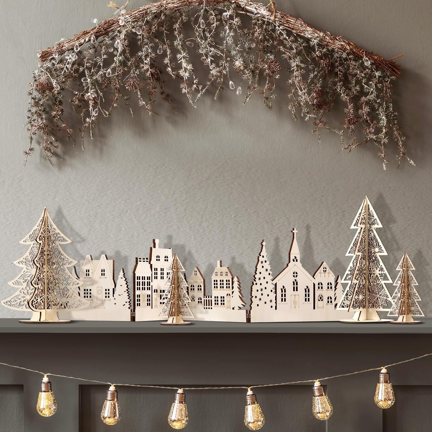 Decorative cityscape with trees and lights on a shelf against a gray wall.
