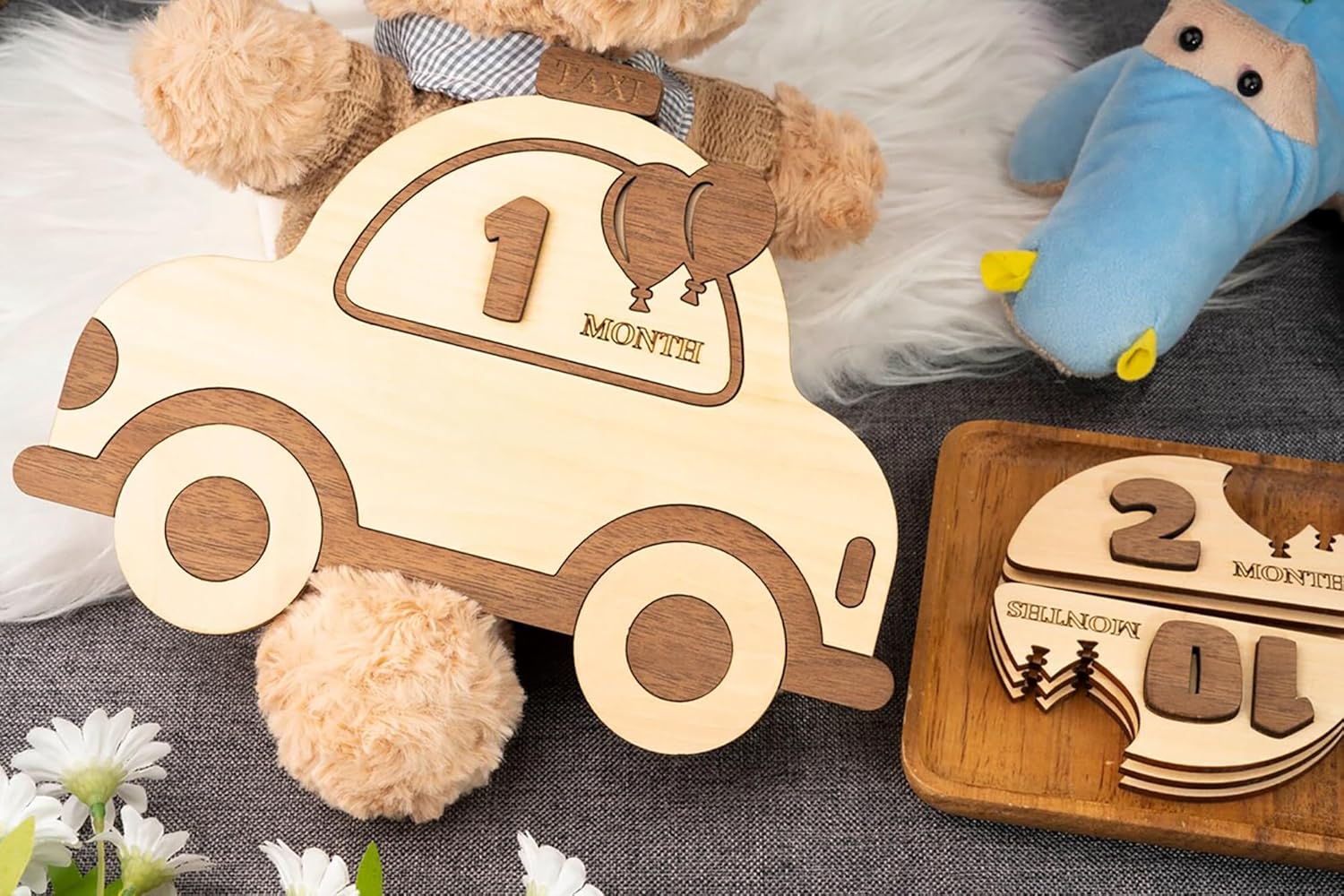 Wooden baby milestone car toys with numbers on a textured surface.