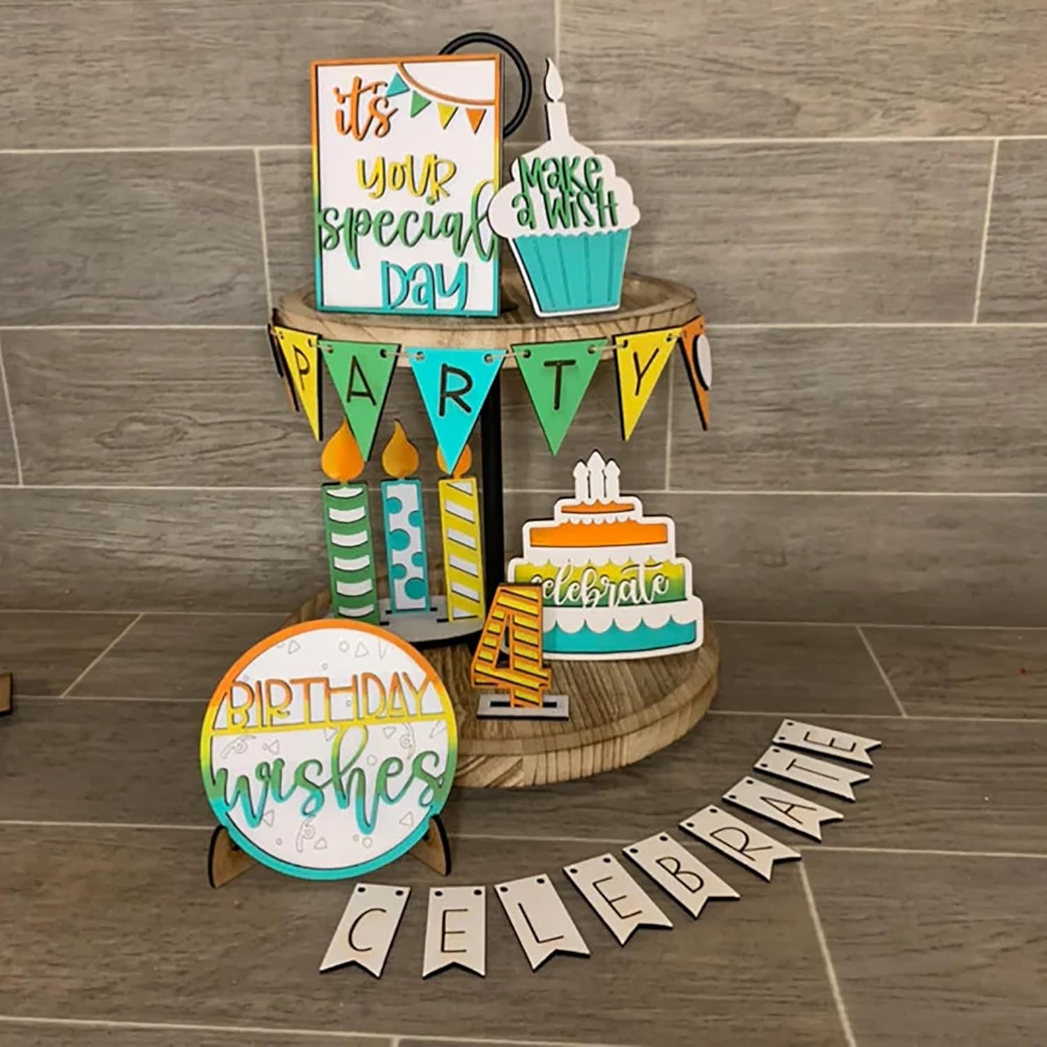 Decorative birthday signs and banners on a wooden stand against a tiled wall.