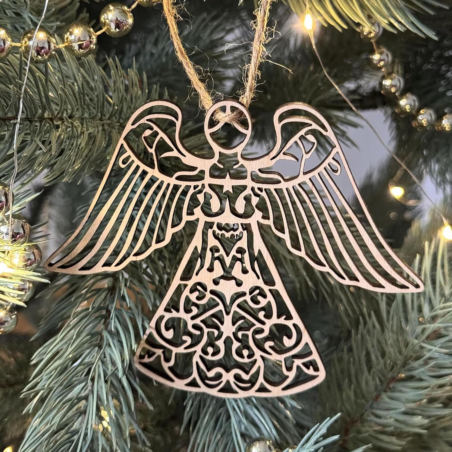 Decorative angel ornament on a Christmas tree with lights in the background