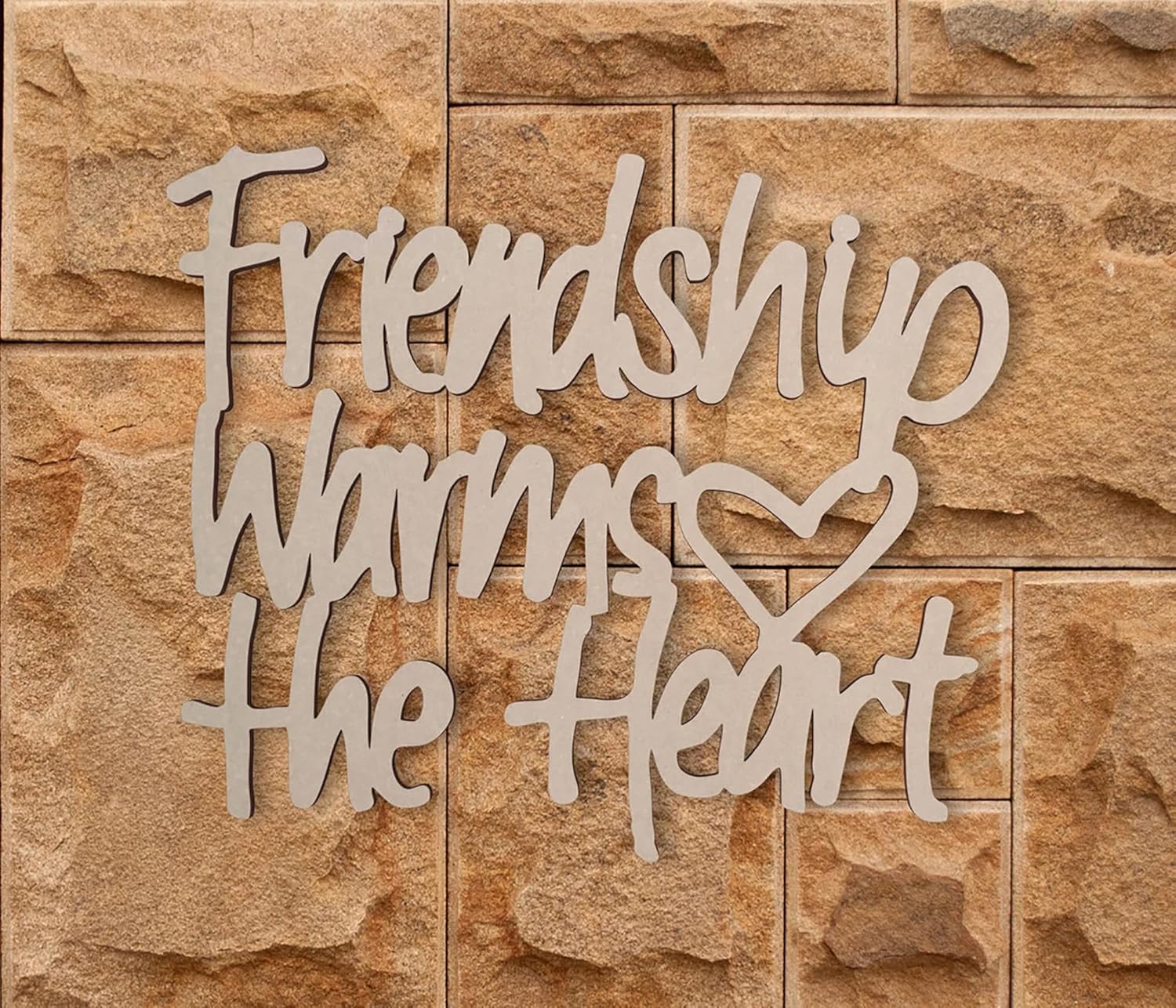 Decorative wall art with 'Friendship warms the heart' text on a stone wall background