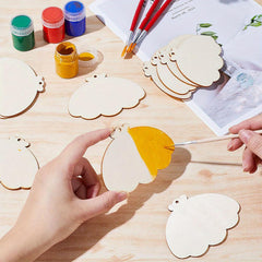 Person painting wooden cloud shapes with yellow paint on a wooden table.