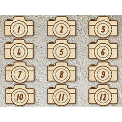 Wooden camera-shaped numbers from 1 to 12 on a textured beige background