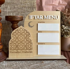 Wooden Iftar menu board with Ramadan Mubarak design on a textured surface.